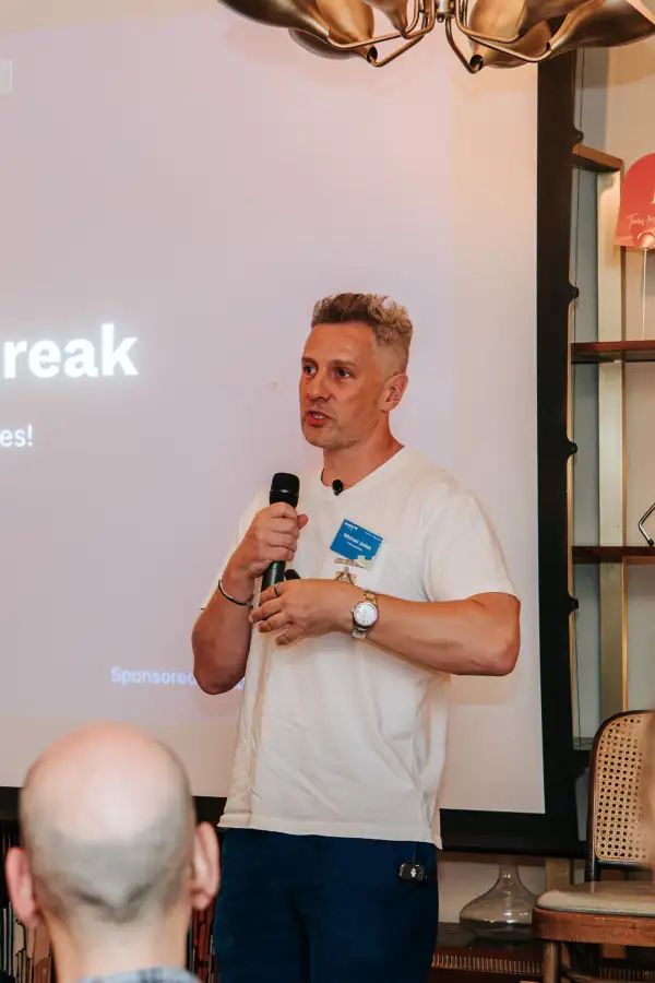 A speaker holding a microphone during a talk at the first loveAI gathering